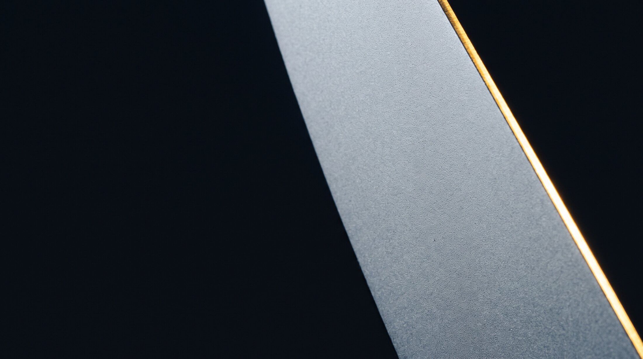 A broad sand-blasted steel plane, one hard gold line along its edge